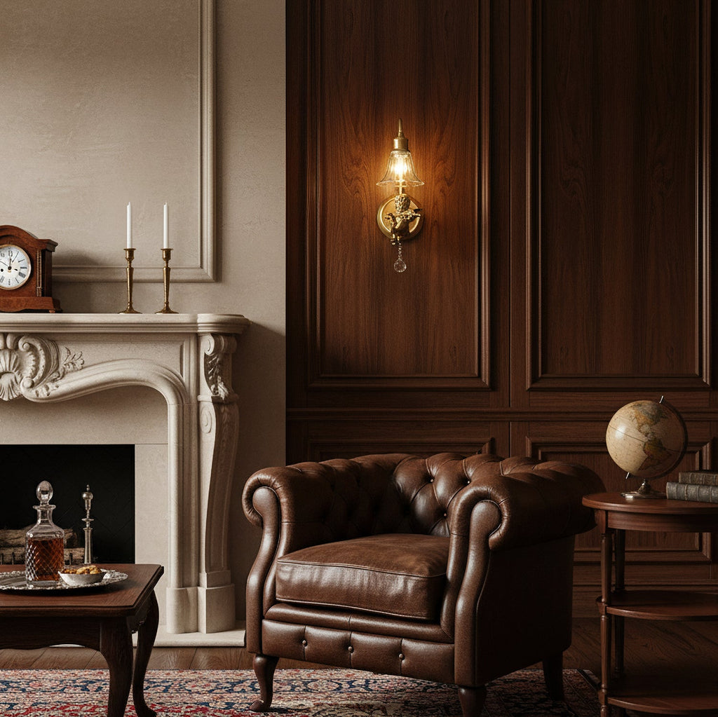 Clérachic gold cherub wall light glowing against dark wood panelling, above a leather armchair and a cream fireplace.