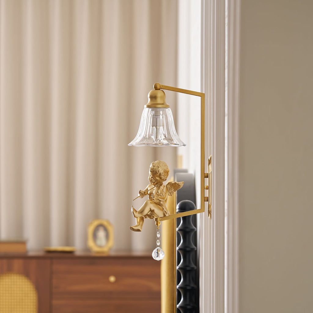 Close view of a gold cherub on a Clérachic wall light, its clear glass bell shade above a wooden chest.