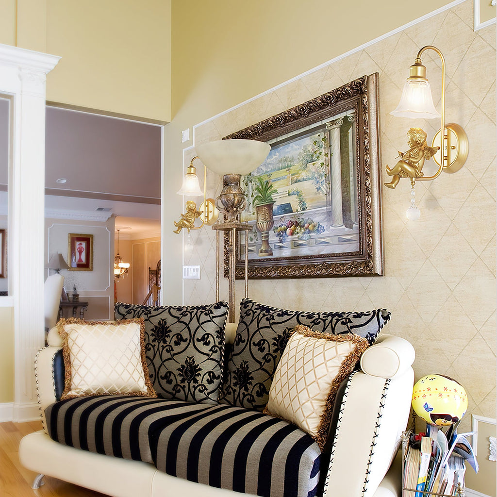Clérachic gold cherub wall light on a diamond-patterned wall, beside a framed painting and a striped sofa with cushions.