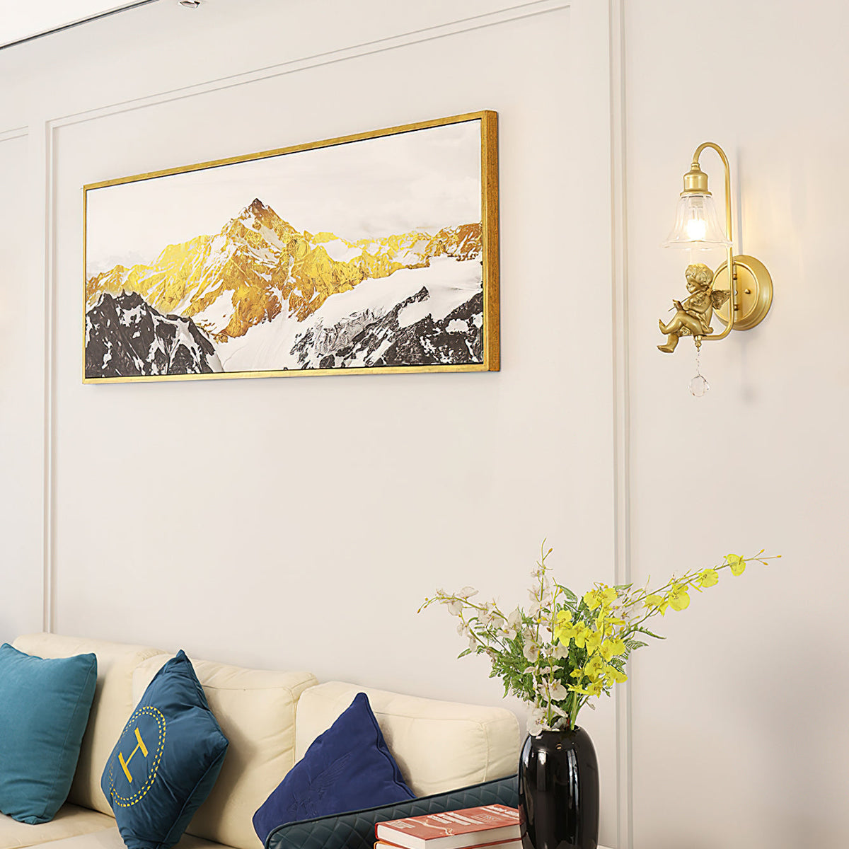 Clérachic gold cherub wall light beside a framed mountain print, above a cream sofa with teal and navy cushions.