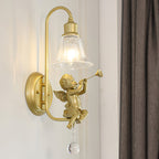 Close view of a gold cherub with a trumpet, a curved arm and a crystal drop on this Clérachic wall light.