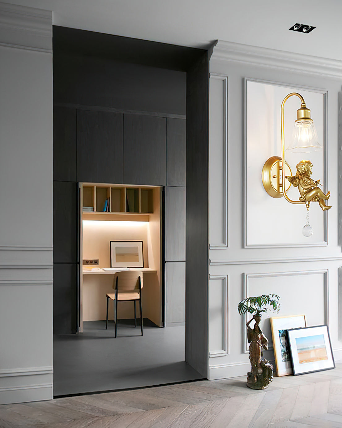 Clérachic gold cherub wall light on a grey panelled wall beside a dark doorway leading to a small desk alcove.