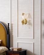 Clérachic wall light with a gold cherub on a panelled wall above a dark nightstand with a cup and a closed book.