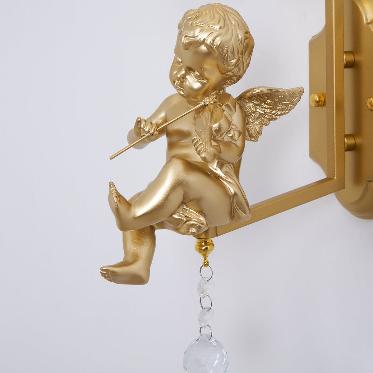 Close view of a gold cherub playing a violin, with a crystal ball drop below on this Clérachic wall light.