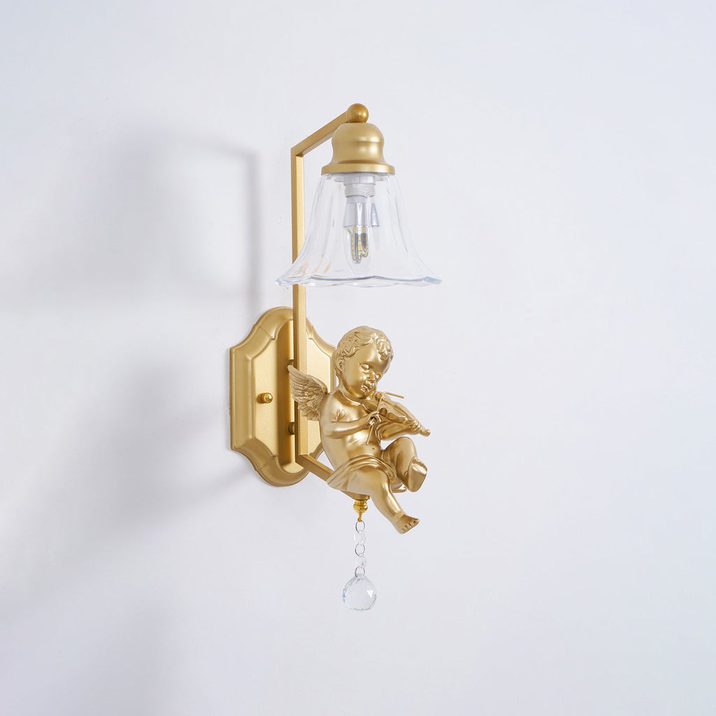 Clérachic gold cherub wall light with a lit clear shade and a violin-playing cherub on a pale wall.