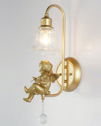 Three-quarter view of a Clérachic gold wall light with a violin cherub, a clear shade and a round backplate.