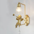Clérachic gold wall light with a trumpet-playing cherub, a square arm and a shaped backplate, on a pale grey wall.