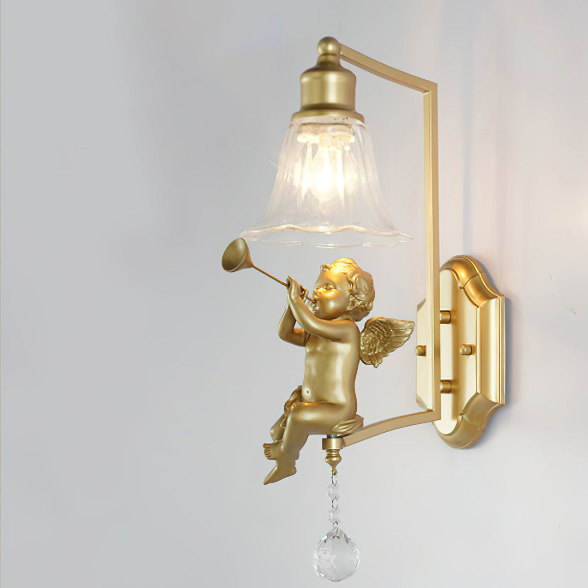 Clérachic gold wall light with a trumpet-playing cherub, a square arm and a shaped backplate, on a pale grey wall.