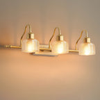 Close view of the glowing ribbed amber glass shades and curved gold arms of a three-light Clérachic wall lamp against a warm wall.