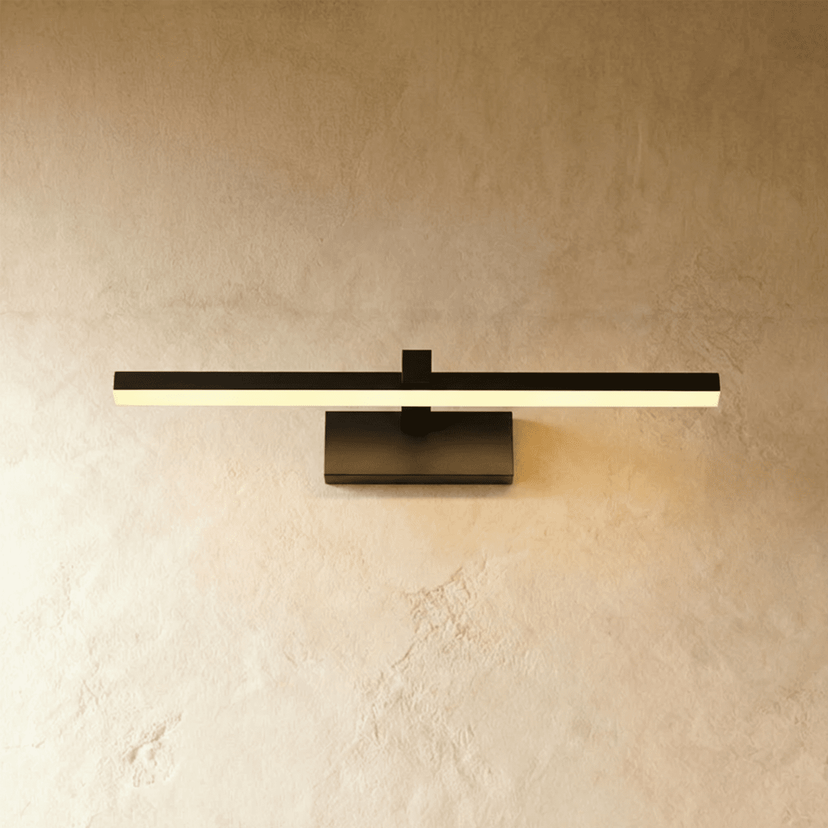 Clérachic black linear wall light with a slim horizontal bar and rectangular wall plate, glowing warm against plaster.