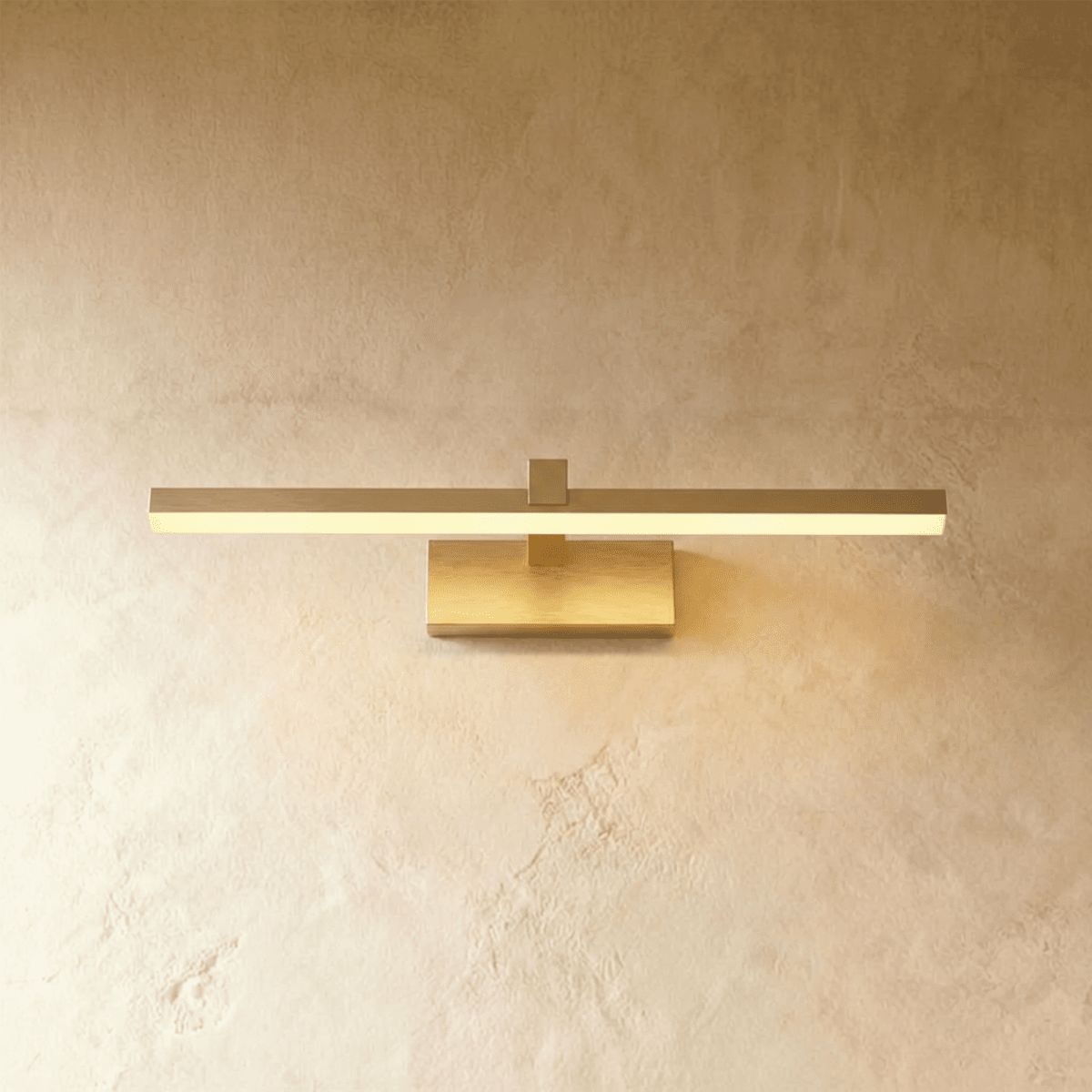 Clérachic brass linear wall light with a slim horizontal bar and rectangular wall plate glowing warm on plaster.