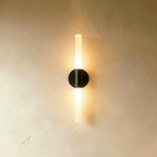 Clérachic Ena wall lamp in black with a frosted glass tube, its round disc mount centered on the wall.