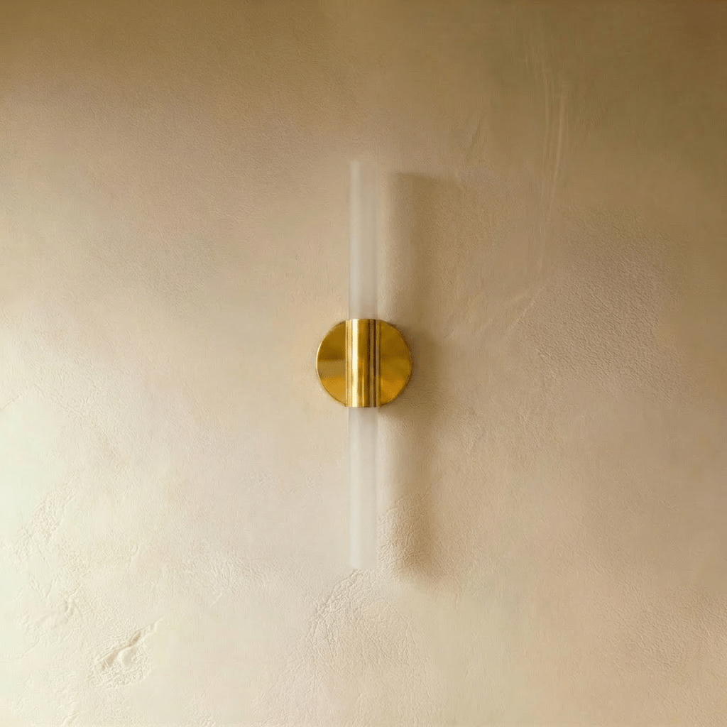 An angled studio view of the Clérachic Ena wall lamp's gold disc mount and frosted glass diffuser.