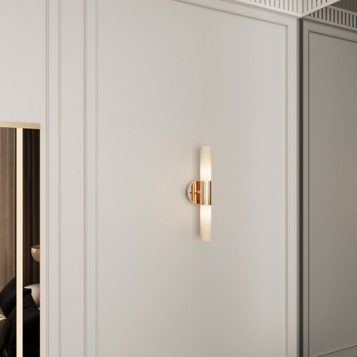A Clérachic Ena wall lamp in gold glows softly on a panelled wall beside a mirrored wardrobe.
