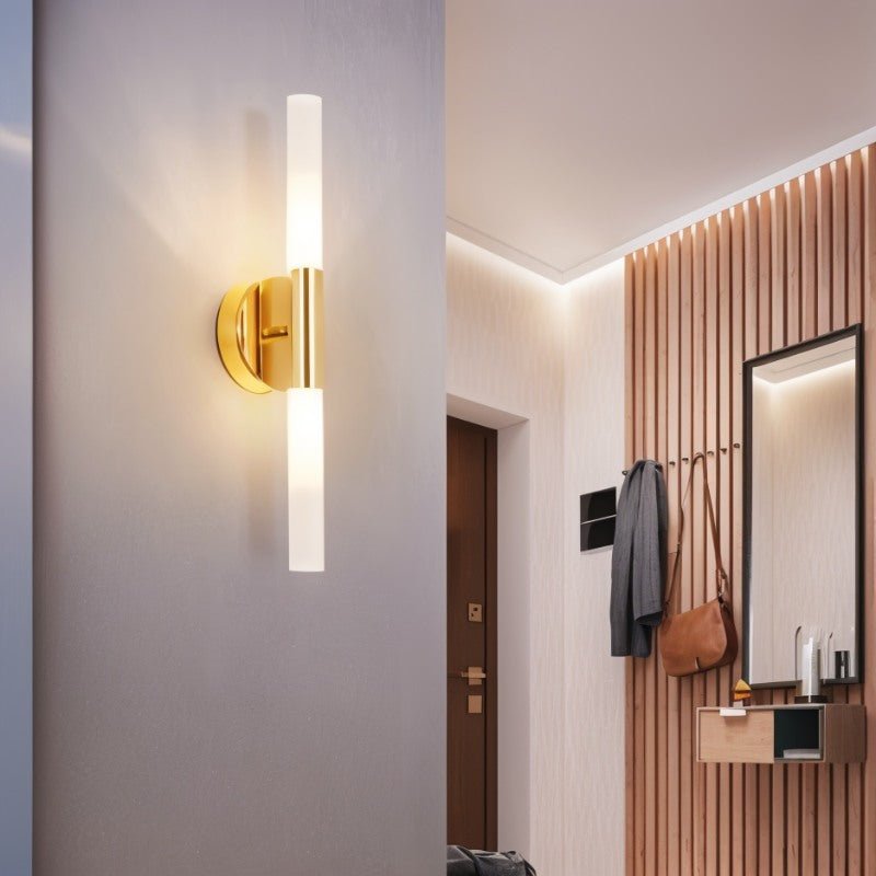 A Clérachic Ena wall lamp in gold lights a hallway corner near a slatted wood entryway wall.