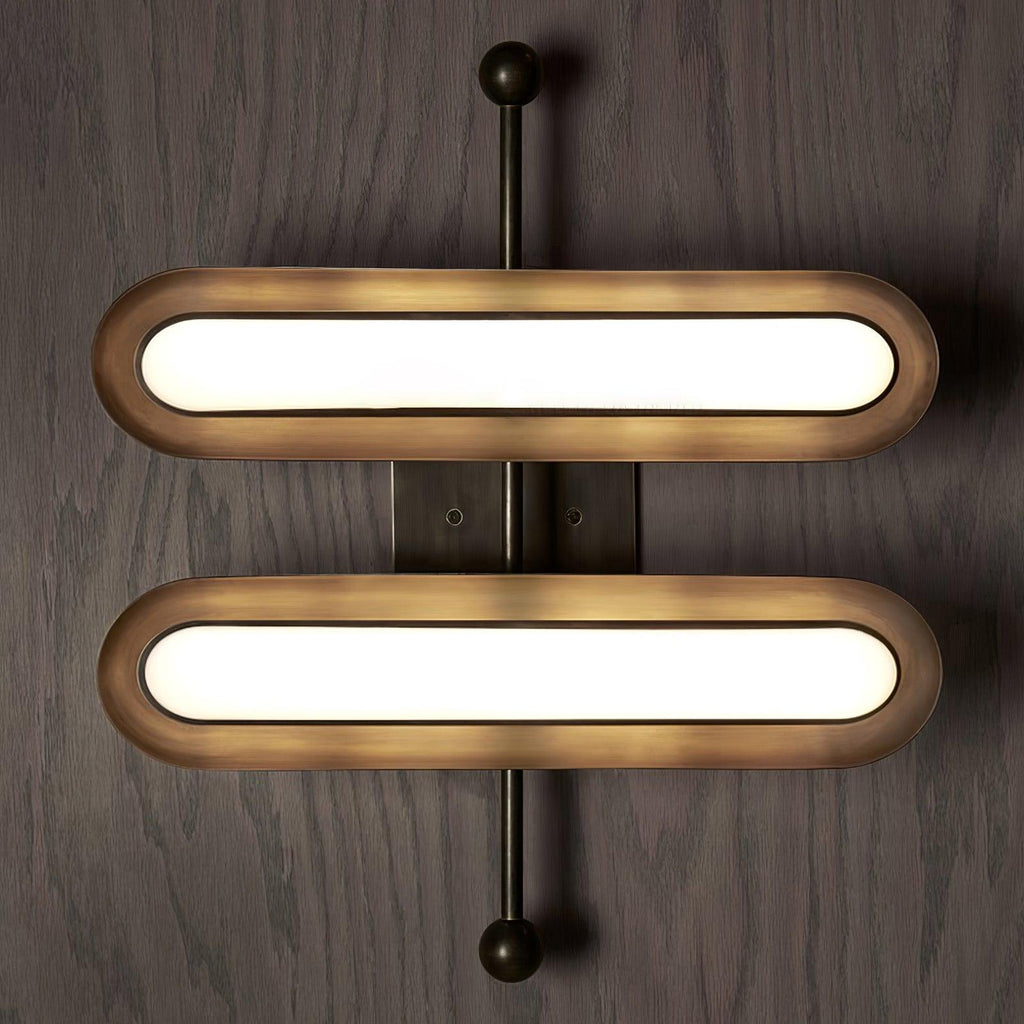 Two stacked capsule lenses in worn gold rims on a vertical black rod with round ends, on a wood-panelled wall, from Clérachic.