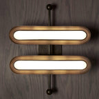 Two stacked capsule lenses in worn gold rims on a vertical black rod with round ends, on a wood-panelled wall, from Clérachic.