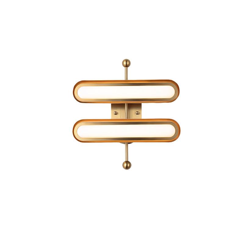 A two-capsule Clérachic wall light with frosted white lenses in gold rims on a brass backplate, shown on white.