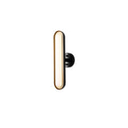 A single Clérachic capsule wall light lit warm on white, with a gold-edged frosted lens and a round black wall plate at the side.