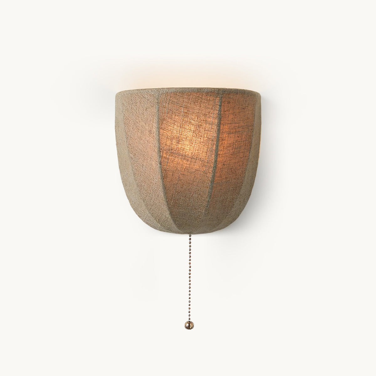Lit linen wall sconce from Clérachic with a seamed half-bowl shade and a beaded pull chain, on a plain white backdrop.