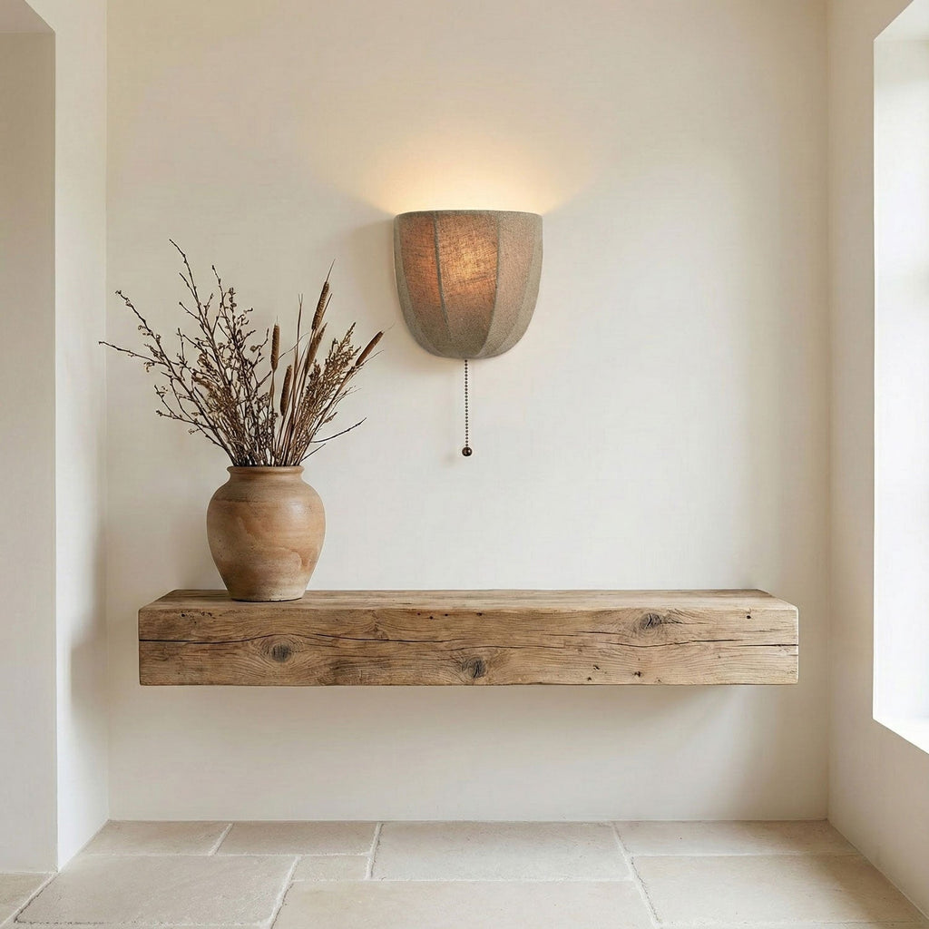 Small Clérachic linen wall sconce above a rough timber shelf holding a clay vase of dried branches.