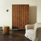 Small Clérachic linen wall sconce high on a cream wall, beside a walnut cabinet and a cream armchair.