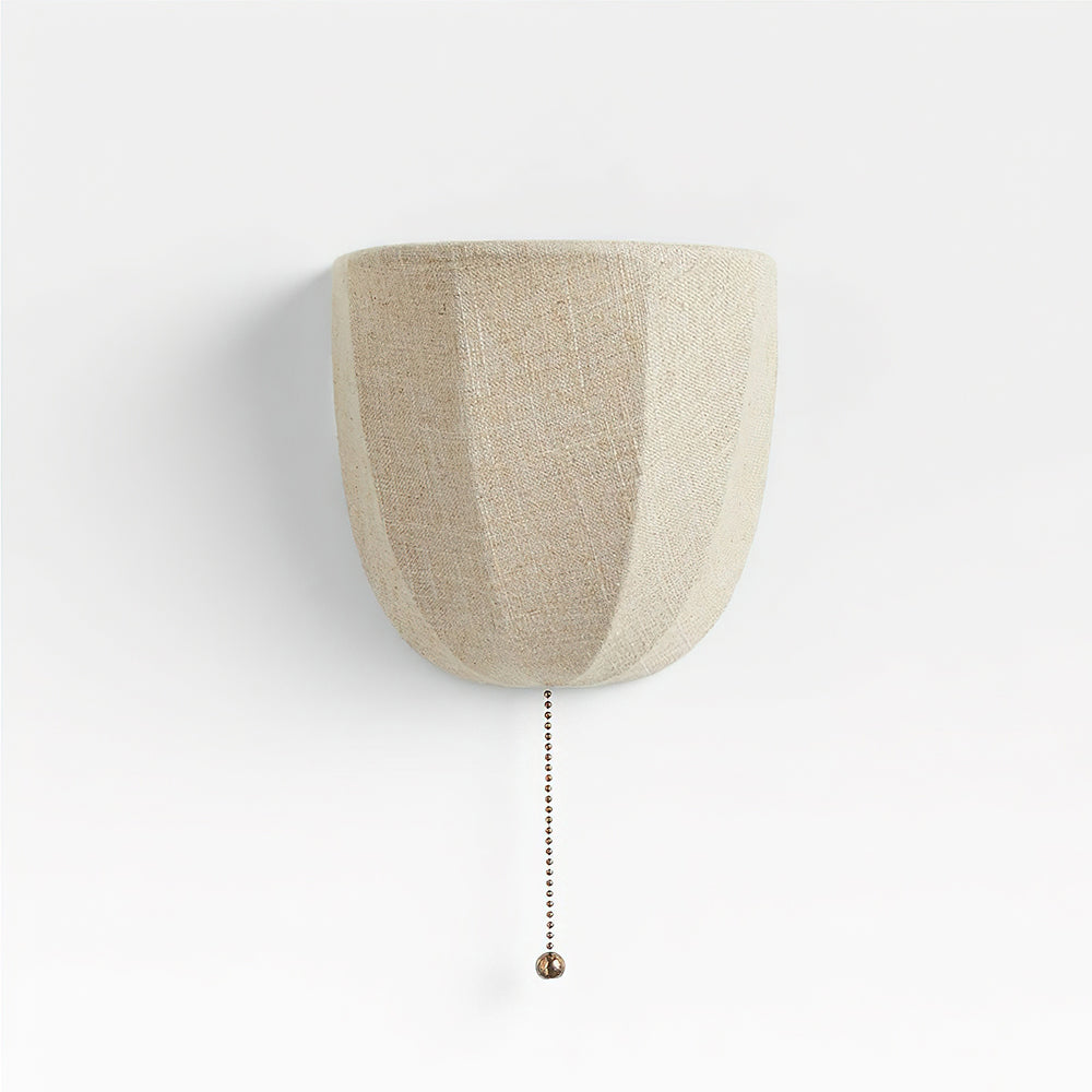 Pale linen Clérachic wall sconce with soft vertical seams and a pull chain, on a white backdrop.