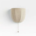 Pale linen Clérachic wall sconce with soft vertical seams and a pull chain, on a white backdrop.