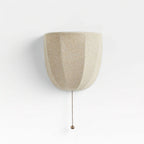 Pale linen Clérachic wall sconce with soft vertical seams and a pull chain, on a white backdrop.