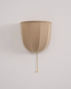 Unlit Clérachic linen wall sconce on a pale wall, with soft vertical seams and a gold-toned pull chain.
