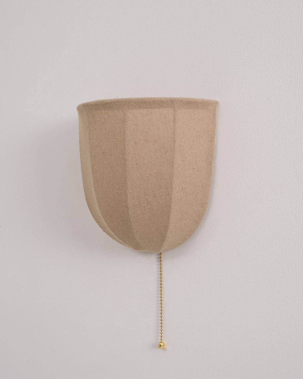 Front view of an unlit Clérachic linen wall sconce with a smooth beige shade and a beaded chain on a pale wall.