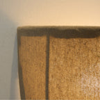 Close view of the stitched linen rim and a dark seam on a lit Clérachic wall sconce.