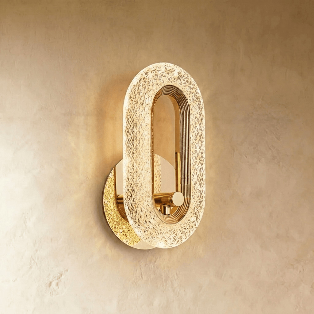 Clérachic gold oval wall lamp with a lit faceted acrylic band and a plain brass knob in the opening, on limewash.