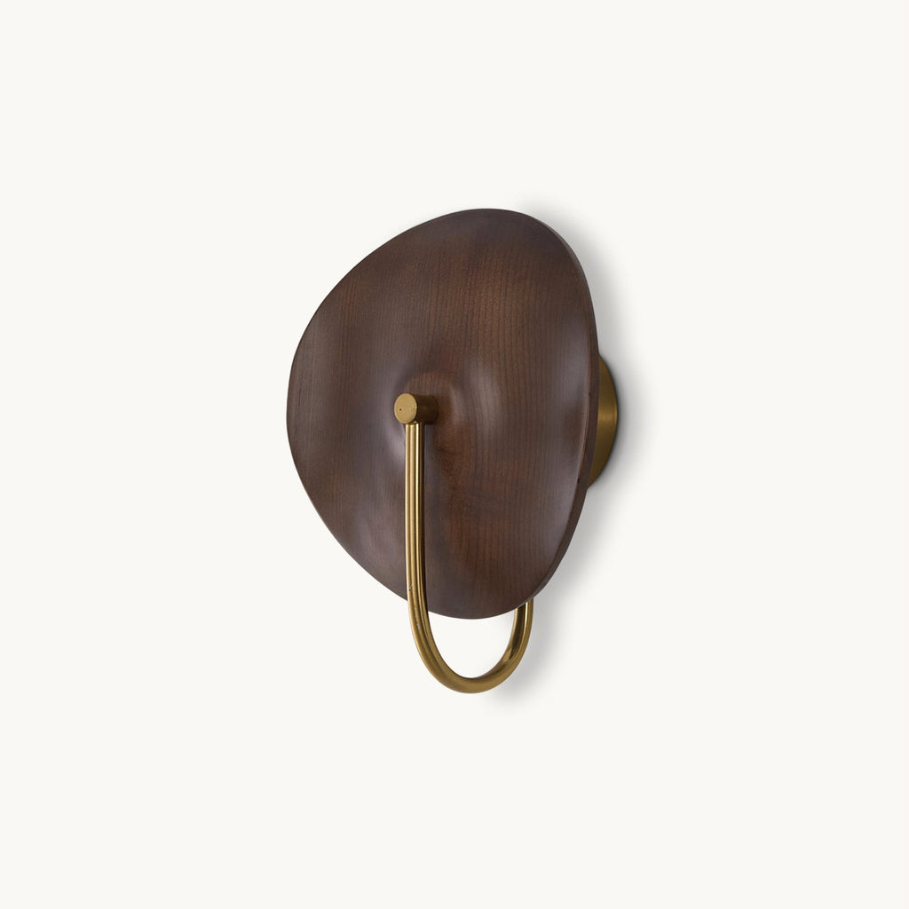 A Clérachic wall light with a walnut-colour wood disc and a gold U-shaped arm, on a plain off-white backdrop.