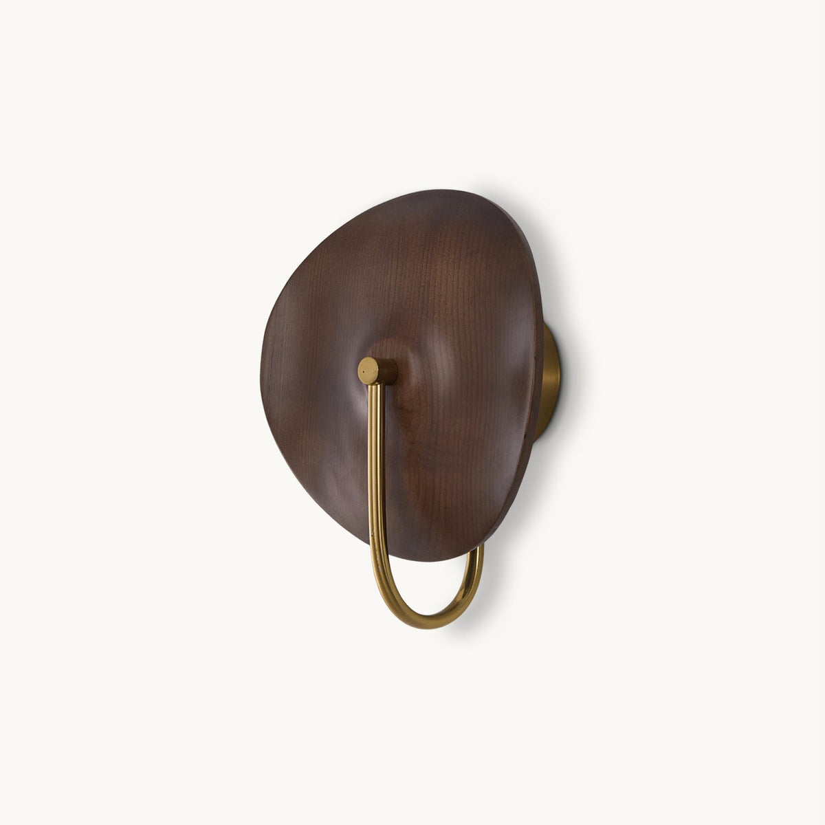 A Clérachic wall light with a walnut-colour wood disc and a gold U-shaped arm, on a plain off-white backdrop.