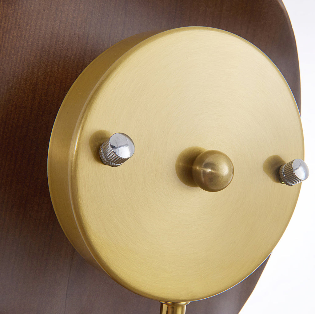 Close view of the brushed gold round backplate on this Clérachic wall light, with two small fixing screws and a central domed cap.
