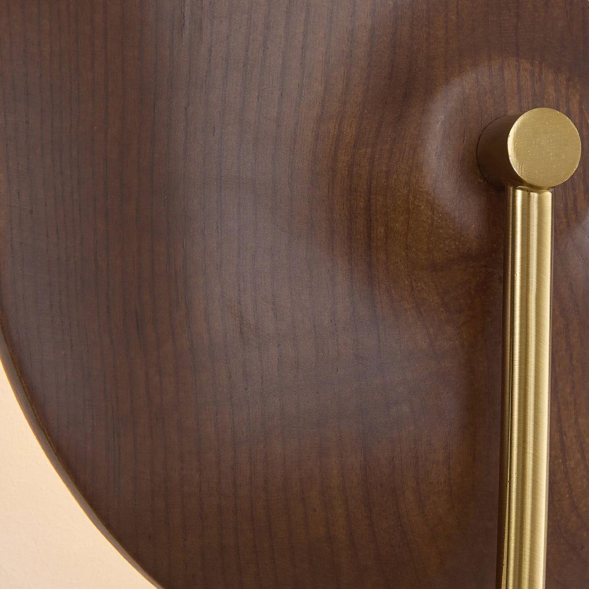 Close view of the wood grain on the walnut-colour disc and the gold rod fixing on this Clérachic wall light.