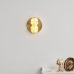 The faceted white shade of this Clérachic sconce glows warm on a pale wall, with a gilt globe ornament and a framed picture below.