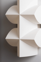 Close view of the white faceted shade, with its curved points and crossed ridges, on this Clérachic wall sconce.