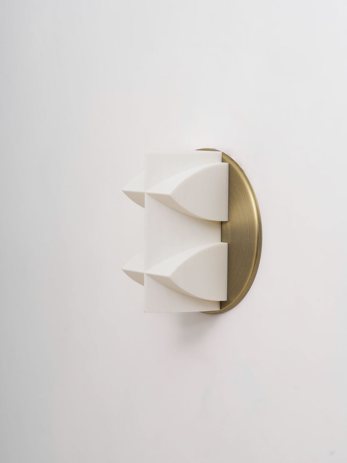 Side view of an unlit white Clérachic wall sconce, two curved points projecting from a brushed gold backplate.