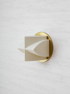 Side view of the unlit white shade on this Clérachic sconce, with one curved point reaching out from a gold disc.