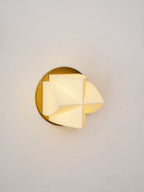Lit Clérachic sconce at a slight angle, the glowing white facets throwing a warm light on the gold disc behind.