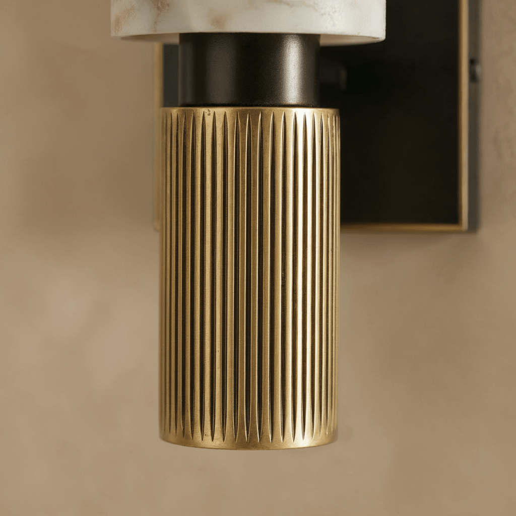 Detail of the Clérachic alabaster sconce's fluted brass base and dark bracket beneath the stone shade.