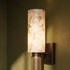 Close view of the Clérachic alabaster sconce lit against an olive green wall in a wood-paneled dining nook.