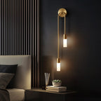 Clérachic's gold stick sconce mounted above a bedside table, its two frosted shades glowing warm white.