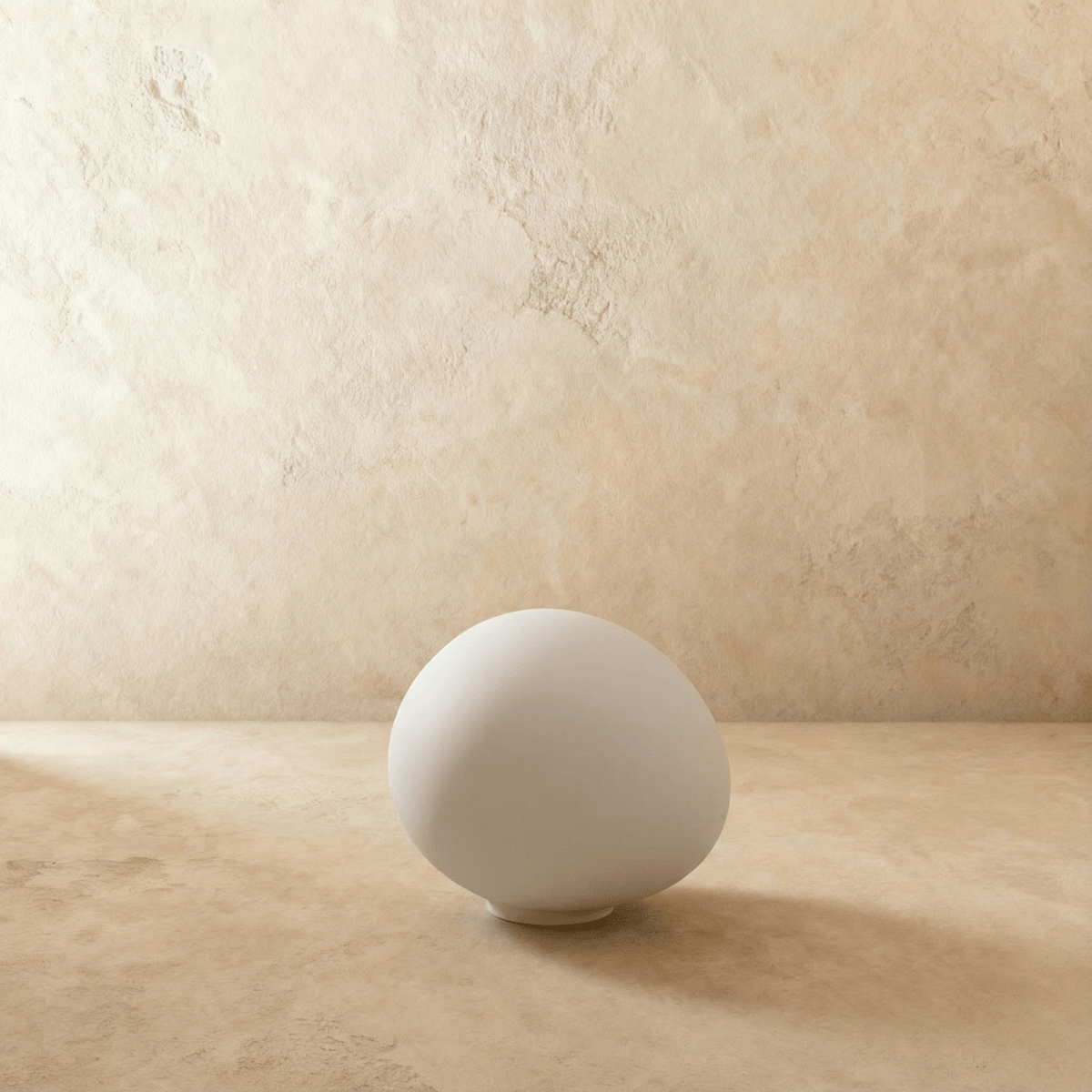 Clérachic frosted white glass goose-egg light switched off, resting on its small white base against a plaster wall.