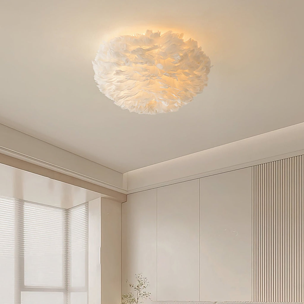 Lit white feather ceiling light from Clérachic on a cream ceiling, with a ribbed wall panel and a soft-curtained window below.