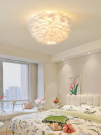 Clérachic white feather ceiling light above a bedroom with a floral duvet, a channelled headboard and a window onto the city.