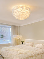 White feather ceiling light from Clérachic lit above a cream bedroom with a ruffled bed, a feather floor lamp and soft curtains.
