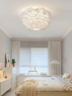 Clérachic white feather ceiling light seen from the doorway of a pale bedroom with a roller blind and a white chest of drawers.